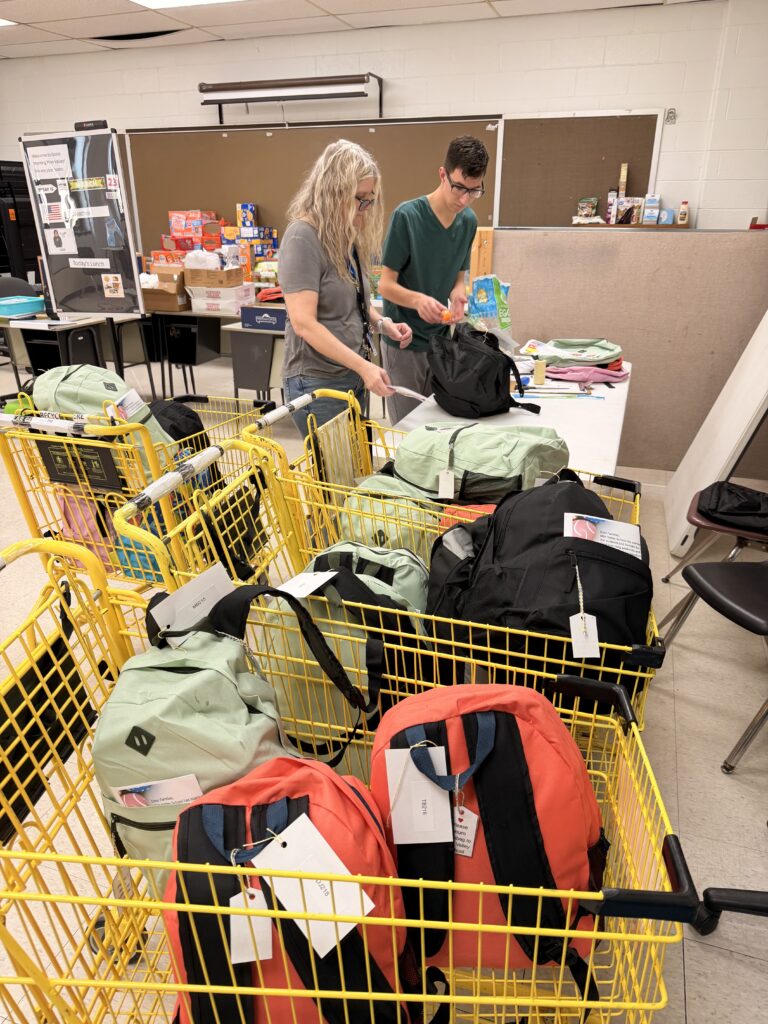 Student and teacher packing donations into school backpacks